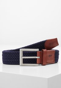 Marineblauwe geweven elastische riem met een zilveren metalen gesp en bruine leren accenten. Kenmerkt zich door een logo dat op de leren flap is geperst.