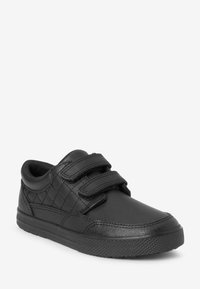 Baskets noires en matériau synthétique avec deux bandes Velcro, un motif matelassé sur les côtés et des semelles en caoutchouc texturé.