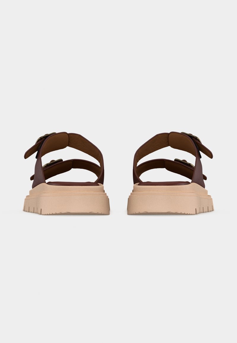 Paire de sandales marron avec des semelles épaisses beige et des brides ajustables, vues de dos sur un fond clair uni.