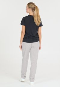 Svart kortärmad t-shirt kombinerad med ljusgrå sweatpants. Mjukt bomullstyg, avslappnad passform, praktisk design och minimal detaljering.