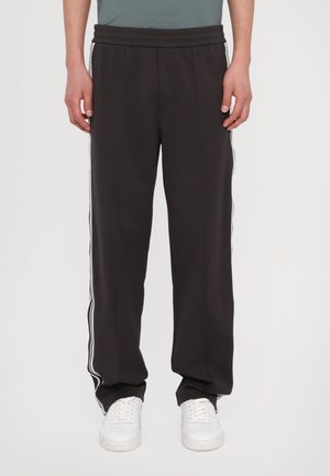 Zwarte, met een ontspannen pasvorm gemaakte sweatpants met een trekkoord in de taille, voorzien van witte zijstrepen. Gemaakt van zacht materiaal, geschikt voor casual kleding.