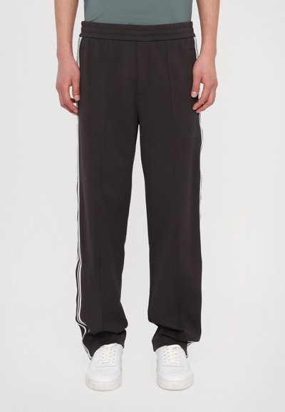 Pantalons de jogging noirs, coupe décontractée, avec taille élastiquée et cordon de serrage, présentant des rayures blanches sur les côtés. Fabriqués en tissu doux, adaptés pour un look décontracté.