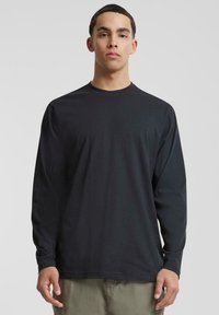 Langermet svart t-skjorte i myk stoff, med rund halsdesign, avslappet passform, med minimale sømmer og uten fremtredende mønstre eller detaljer.