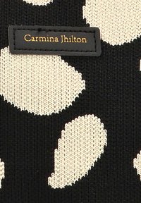 Textil negro con un patrón abstracto de hojas beige. Presenta una etiqueta rectangular con la inscripción "Carmina Jhilton" en hilo dorado.