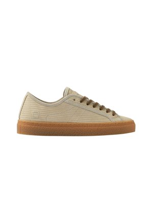 Beige lage sneaker met geribbelde textuur, bruine veters en rubberen zool, in profiel naar rechts tegen een witte achtergrond.