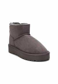 Stivaletti alla caviglia in suede grigio con fodera morbida, punta arrotondata e suola piatta in gomma con motivo testurizzato. Cuciture semplici in evidenza.