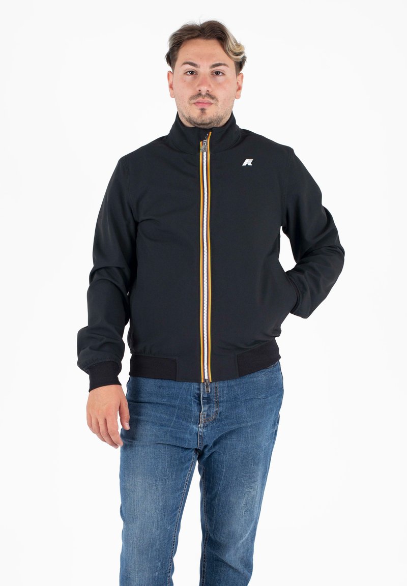 Zwarte jas met een staande kraag, ritssluiting en kleurrijke streepaccenten. Te combineren met blauwe jeans, met een ontspannen pasvorm en zichtbare naden.
