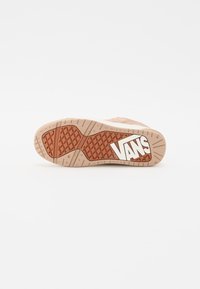 Tanganica na Vans tenisicama s bež i narančastim dizajnom, koja ima dijamantne uzorke i istaknuti bijeli logo. Glatka tekstura i čvrsti materijali.