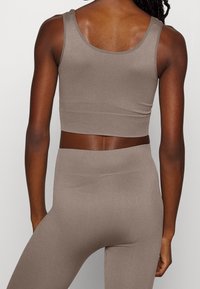 Top corto de canalé marrón y leggings a juego, que presentan un diseño ajustado, textura suave y una cinturilla sin costuras sin hardware visible.