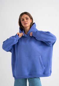 Felpa oversized blu in misto cotone, con tasca a marsupio, polsini a coste e un ampio cappuccio regolabile.