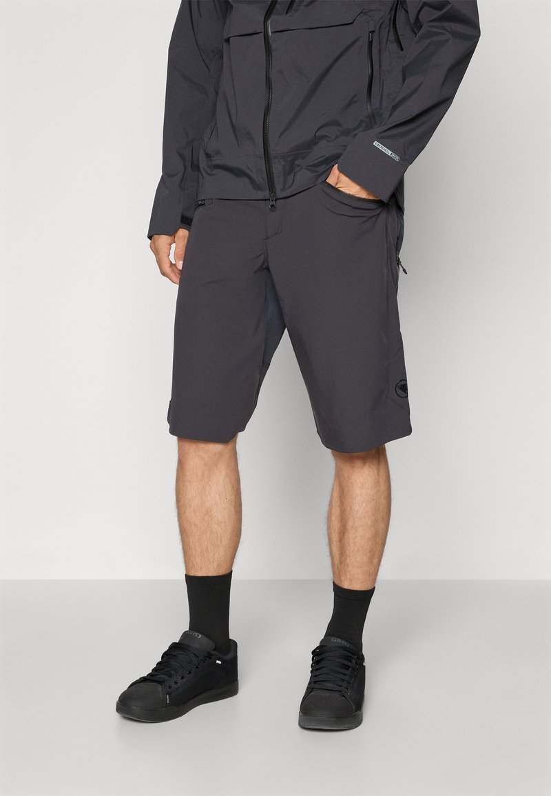 Bermudas de hombre en gris oscuro, confeccionadas con material ligero, que cuentan con un corte relajado, dos bolsillos laterales y un acento de logo en la parte inferior de la pierna.