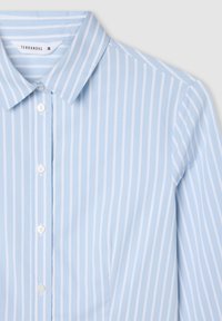Camicia blu chiaro con bottoni, caratterizzata da sottili righe bianche verticali, colletto classico e una texture del tessuto liscia. Etichetta del marchio visibile all'interno del colletto.