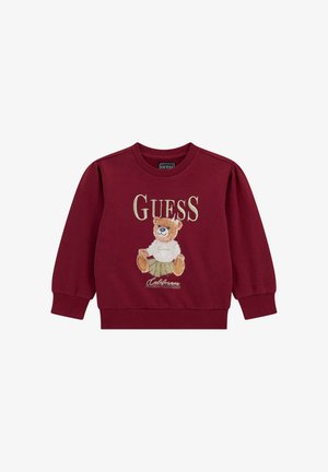 Burgundy színű pulóver, amelyen egy plüssmackó hímzés, a "GUESS" logó és ribbelt mandzsetta, valamint szegély található. Puha pamut anyag, laza fazonnal.