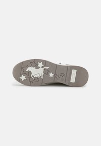 La semelle de sneaker de couleur claire présente une silhouette de cheval avec des accents d'étoiles, une texture antidérapante et une marque. Design plat avec des bords striés.