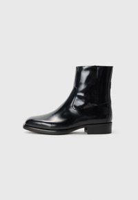 Botines de piel negra con un acabado brillante, diseño elegante y punta redonda. Cuentan con paneles laterales elásticos y un tacón bajo en bloque.