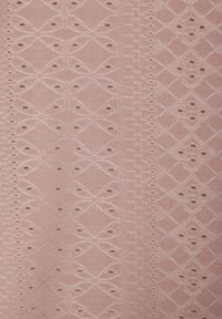 Tissu rose clair présentant un motif de diamants avec des cercles ajourés et des broderies délicates. Texture lisse avec un léger éclat.