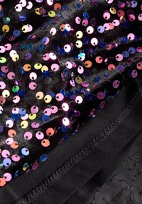 Tissu noir orné de sequins ronds multicolores disposés de près, avec une texture lisse et un aspect superposé. L'ourlet présente un bord soigneusement cousu.