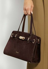 Dark brown suede handbag with a structured design, gold-tone hardware, a strap detail, and double top handles. Features embossed logo.