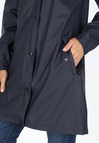 Granatowa wodoodporna kurtka z zapięciem na napy z przodu, elastycznymi mankietami i bocznymi kieszeniami. Gładka faktura i klasyczny krój.