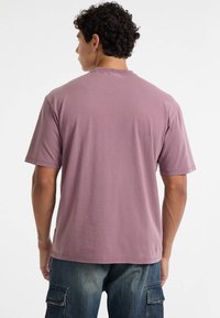 Korte mouwen, ronde hals t-shirt van zacht lavendel katoen, met een relaxte pasvorm en minimale stikdetails bij de hals en zoom.