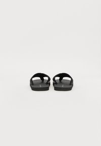 Sandale negre tip flip-flop, cu talpă plată și bretele din cauciuc. Suprafața tălpii este texturată pentru a oferi aderență. Design minimalist, fără accente suplimentare.