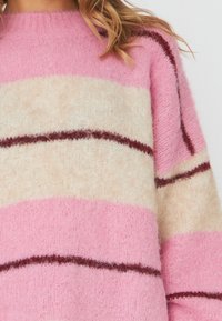 Gestreifter Strickpullover mit rosa, creme und burgunderfarbenen Streifen. Weicher Stoff, Rundhalsausschnitt und leicht oversized Passform.