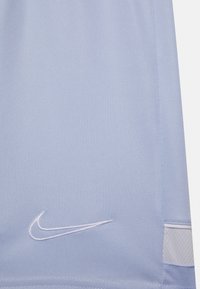 Světle modré látkové šortky s bílým vyšitým logem Nike na lemu. Materiál má hladký povrch a boční detail z prodyšné síťoviny.