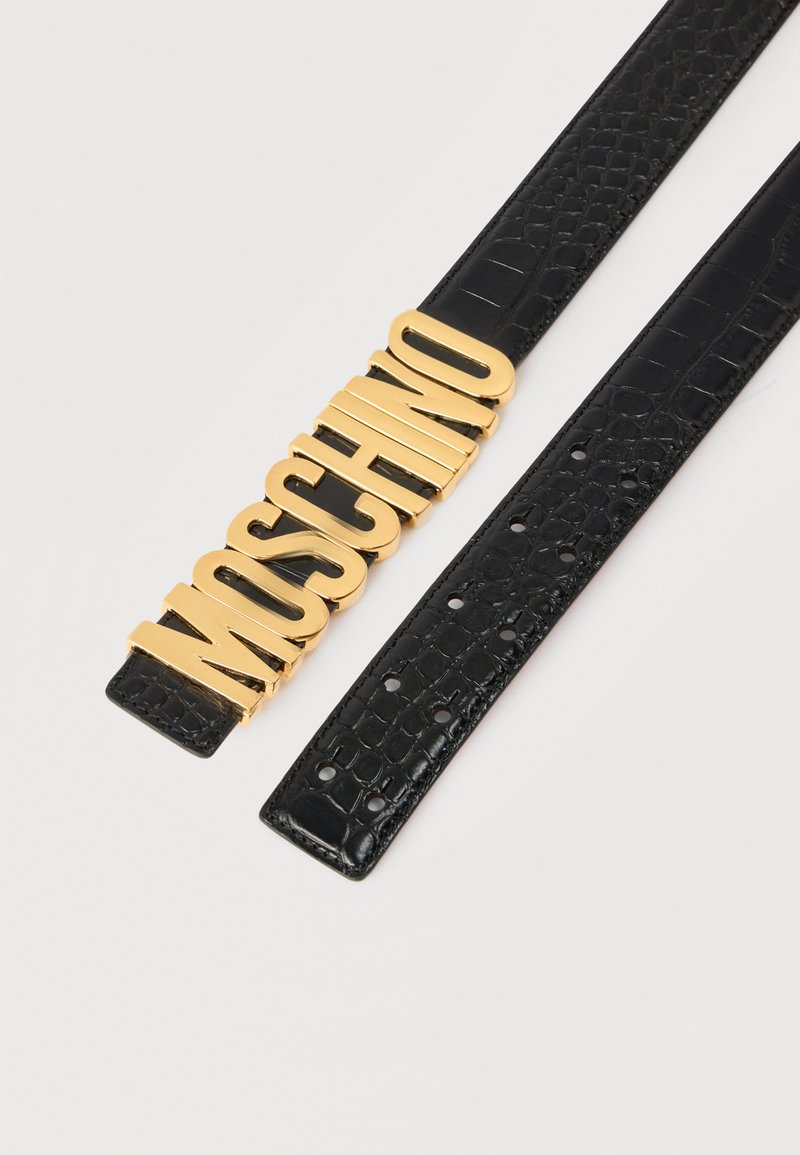Black textured leather belt with multiple holes and large gold letters spelling "MOSCHINO" as the buckle.
