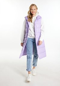 Vesta puffer de culoare mov deschis, cu glugă, având un design lung și nasturi tip snap, purtată peste un hanorac alb și blugi. Adidași albi.