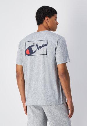Camiseta de manga corta gris hecha de una mezcla de algodón, con un gran logo en la parte posterior en azul marino y rojo dentro de un contorno rectangular.