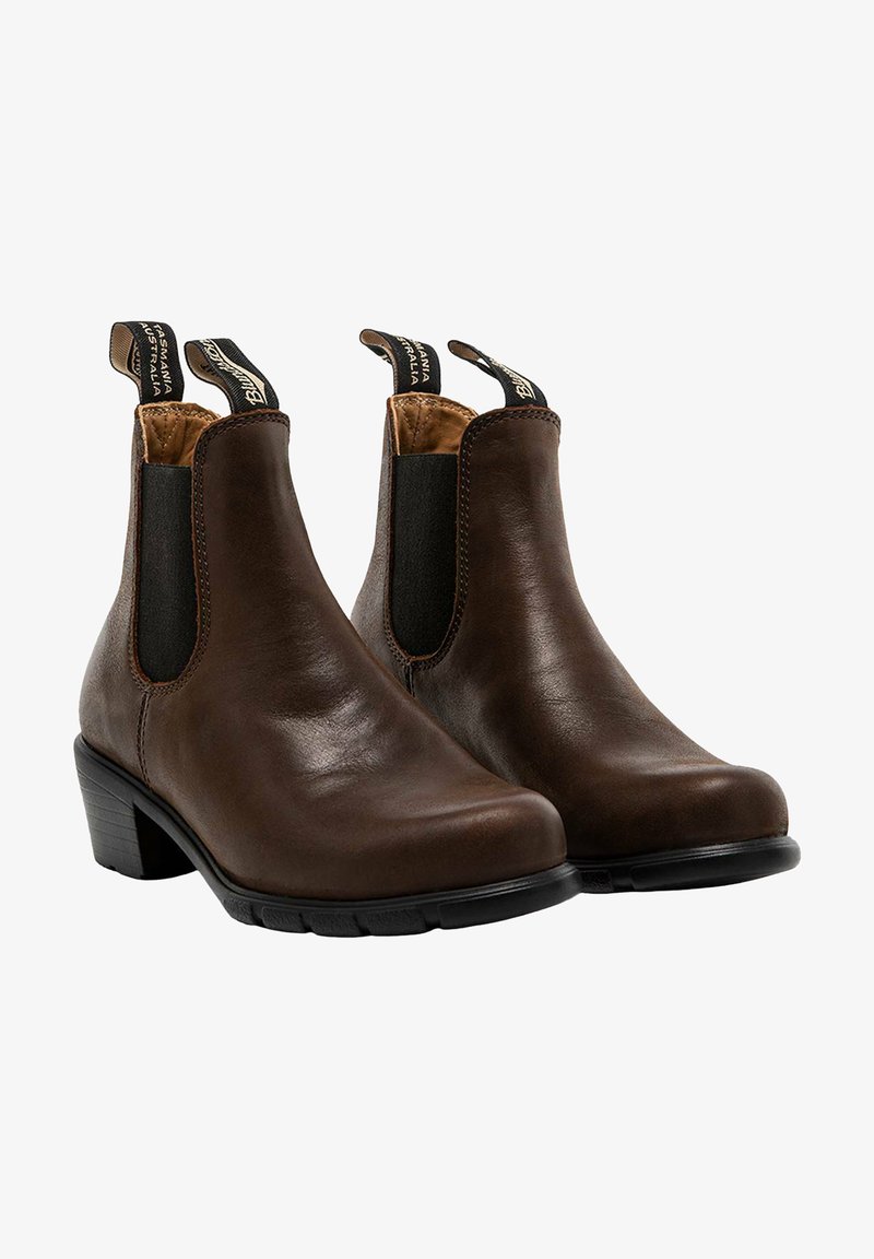 Bottines en cuir marron avec des panneaux élastiques sur les côtés, des orteils arrondis et des talons bas en bloc. Dotées de languettes pour un enfilage facile. Semelles en caoutchouc texturé.