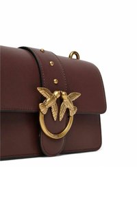 Borsa in pelle bordeaux con chiusura a forma di uccello dorato, caratterizzata da borchie dorate sul risvolto e un design liscio e strutturato.