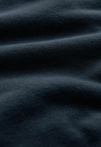 Donkerblauwe stof met een gladde, licht gestructureerde oppervlakte en een subtiele rek, met een uniforme weefpatroon door de hele stof.