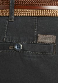 Pantalons en denim foncé avec une ceinture en cuir brun et tressée. Présente une fermeture à bouton et une étiquette en cuir avec "MEYER" cousue.