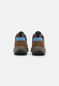 Brown suede and mesh sneakers feature a blue logo patch on the heel, black accents, and a sturdy rubber sole with textured tread.