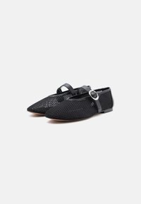 Schwarze Netz-Spitzschuhe mit Knöchelriemen und silbernen Schnallen, auf einem weißen Hintergrund, seitlich nebeneinander leicht nach links geneigt.