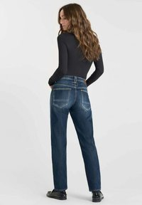 Jeans de mezclilla de tiro alto en azul oscuro con pierna recta. Cuenta con dos bolsillos traseros y una etiqueta de cuero en la cintura. Textura suave.