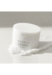 Pot circulaire blanc de baume nettoyant doux avec une texture lisse, étiqueté "NEEDLY Baume nettoyant doux", contenant de l'huile de graine de Camellia Japonica.