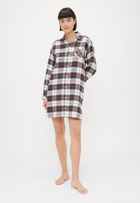 Abito camicia a quadri bianco, rosso e verde. Presenta una tasca sul petto a sinistra con un motivo colorato. Realizzato in tessuto morbido, vestibilità comoda.