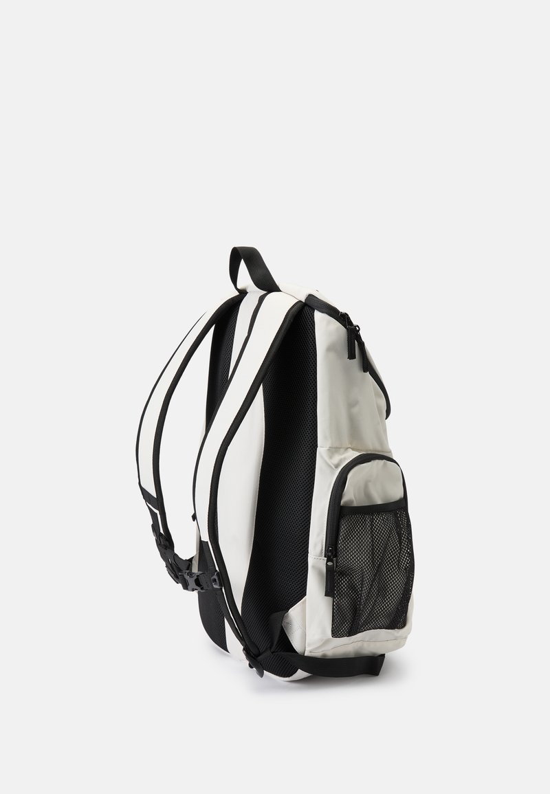White and black backpack with a mesh side pocket, adjustable straps, and a smooth, durable fabric exterior. Curved shape for ergonomic fit.