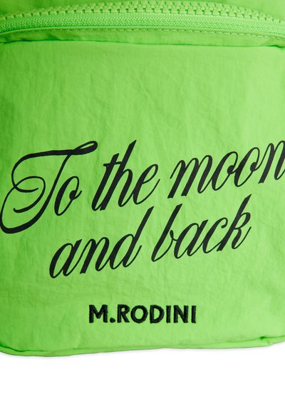 Φωτεινό πράσινο ύφασμα με φερμουάρ, με μαύρο κείμενο σε στυλ γραφής που γράφει «Στο φεγγάρι και πίσω» και «M.RODINI» από κάτω.
