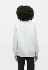 Γκρι φούτερ με στρογγυλή λαιμόκοψη, κατασκευασμένο από απαλό ύφασμα με ριμπ μανσέτες και τελείωμα. Χαλαρή εφαρμογή με ελαφρώς κατεβασμένους ώμους. Μινιμαλιστικός σχεδιασμός.