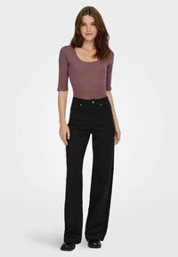 Sorte vide ben jeans parret med en tætsiddende mauve ribbet langærmet top, der fremviser en rund halsudskæring og 3/4-ærmer.