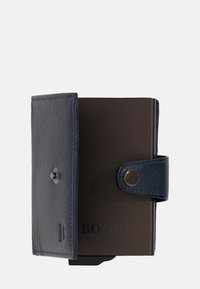 Ādas maciņš tumši zils un brūns, ar reljefu tekstūru, aizdari ar pogu un iegravētu logo. Kompakts dizains ar drošu aizdari.