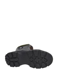 Bota negra con una suela robusta, que presenta tacos pronunciados y una superficie texturizada. Acentos verdes y naranjas alrededor de la zona del tobillo.