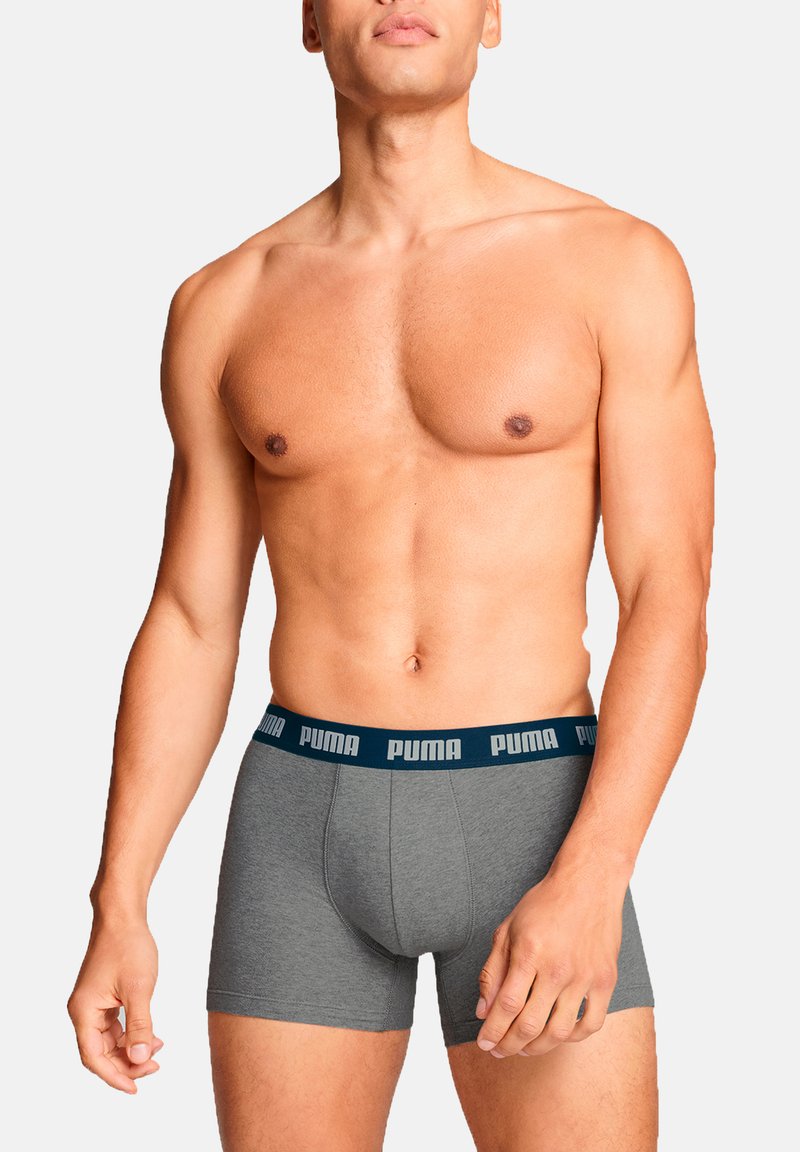 Graue Boxershorts mit einem dunkelblauen elastischen Bund, der das "PUMA"-Logo trägt. Glatte Textur, eng anliegendes Design, mittlere Oberschenkellänge.