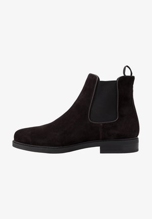 Bota Chelsea de ante negro con panel elástico lateral, talonera para facilitar el calzado y suela baja apilada.
