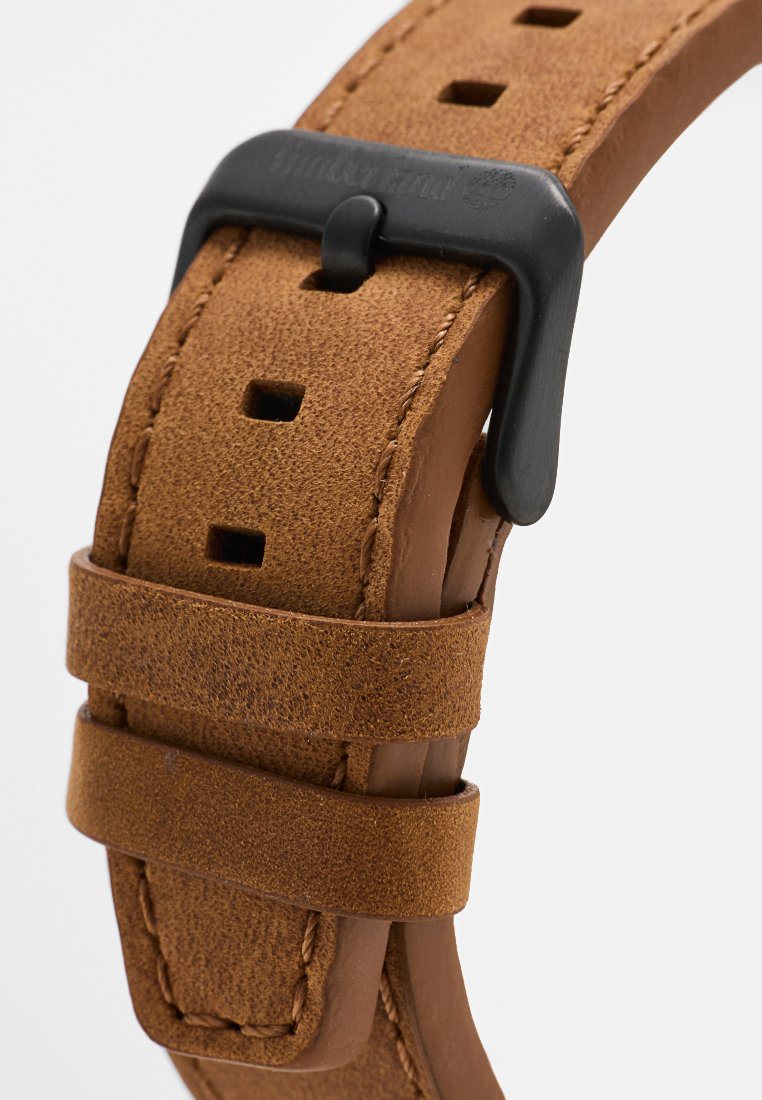 Correa de reloj de cuero marrón con acabado texturizado, que presenta múltiples agujeros de ajuste y una hebilla de metal negro.