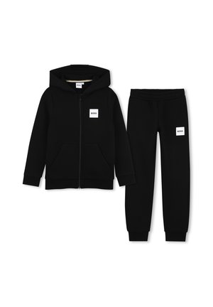 Zwarte hoodie met ritssluiting aan de voorkant en bijpassende zwarte joggingsbroek, beide met witte vierkante logo's met het woord "BOSS" op de borst en dij.