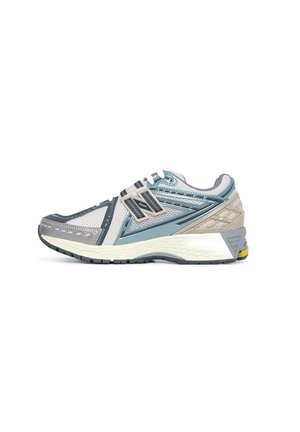 Zapatilla de running ligera en malla gris y azul con detalles texturizados, acentos reflectantes y una suela blanca acolchada con un toque amarillo.